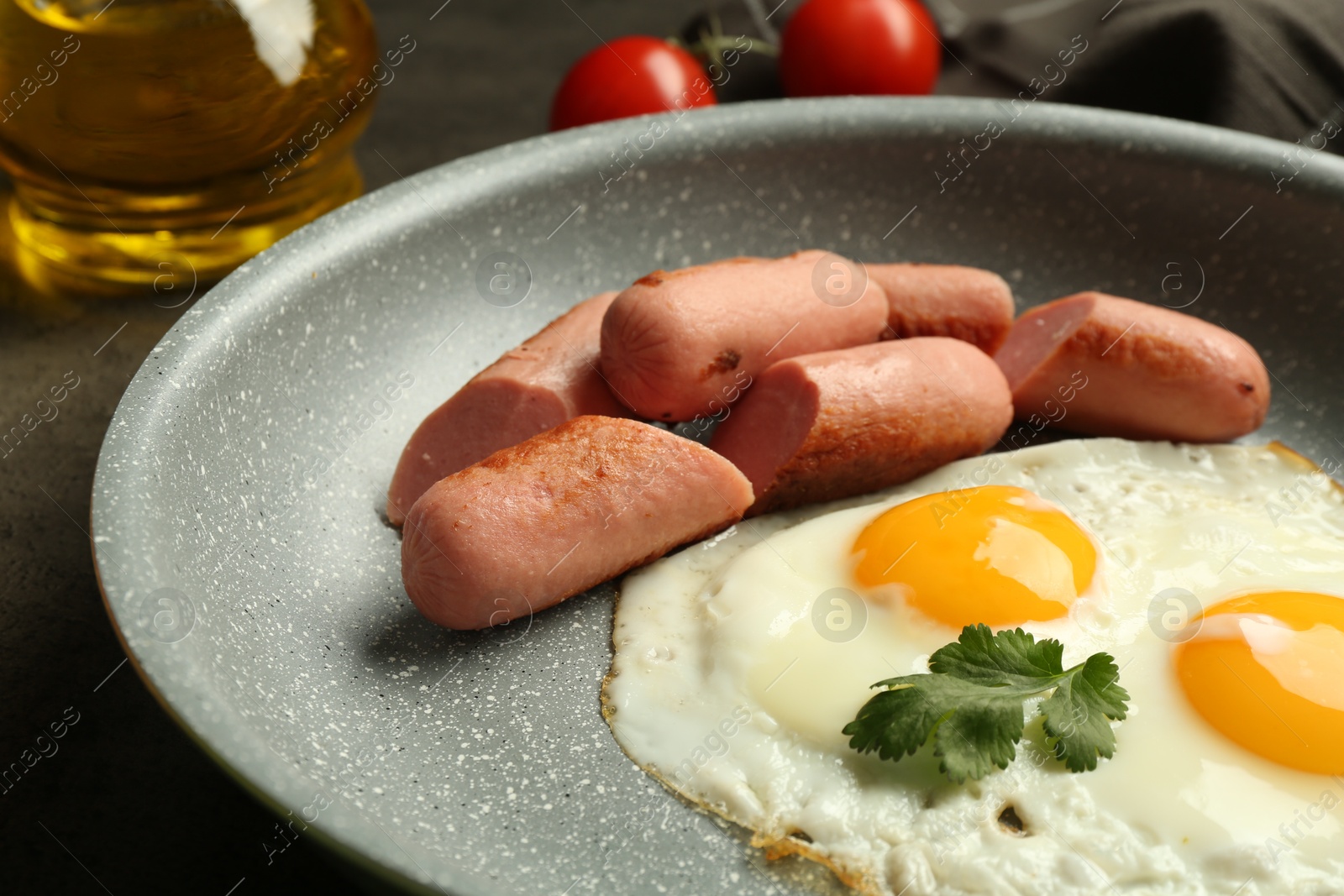 Photo of Tasty fried eggs and sausages served on grey table, closeup