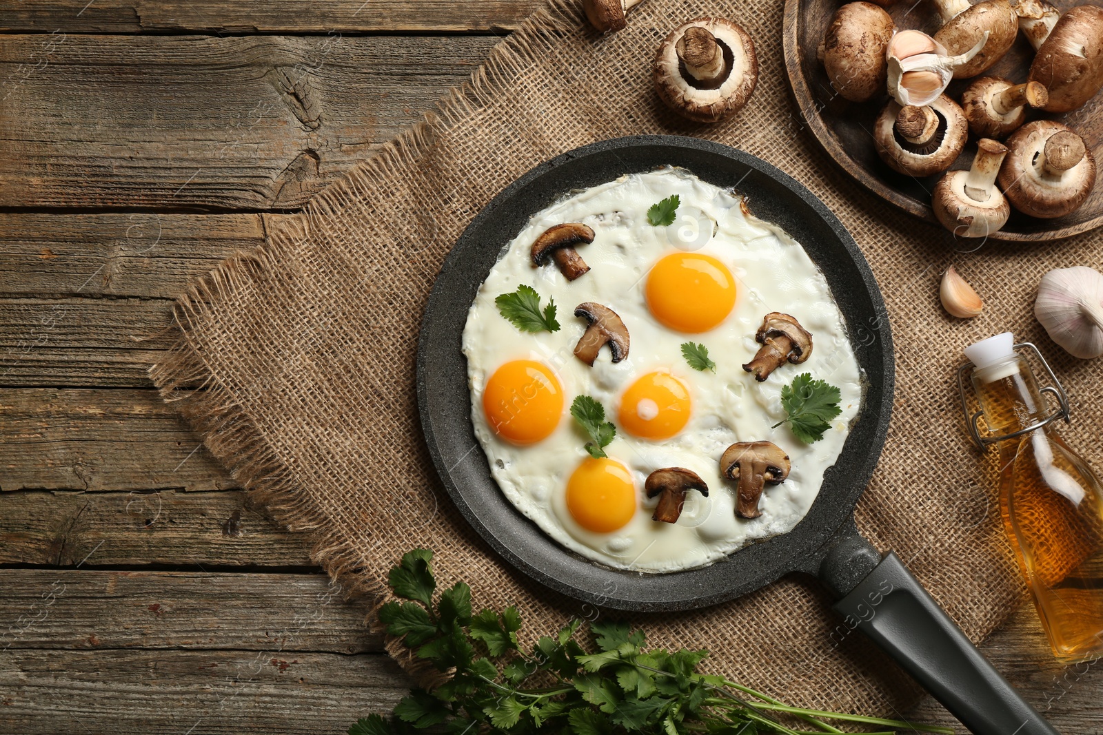 Photo of Tasty fried eggs with mushrooms and parsley served on wooden table, flat lay. Space for text