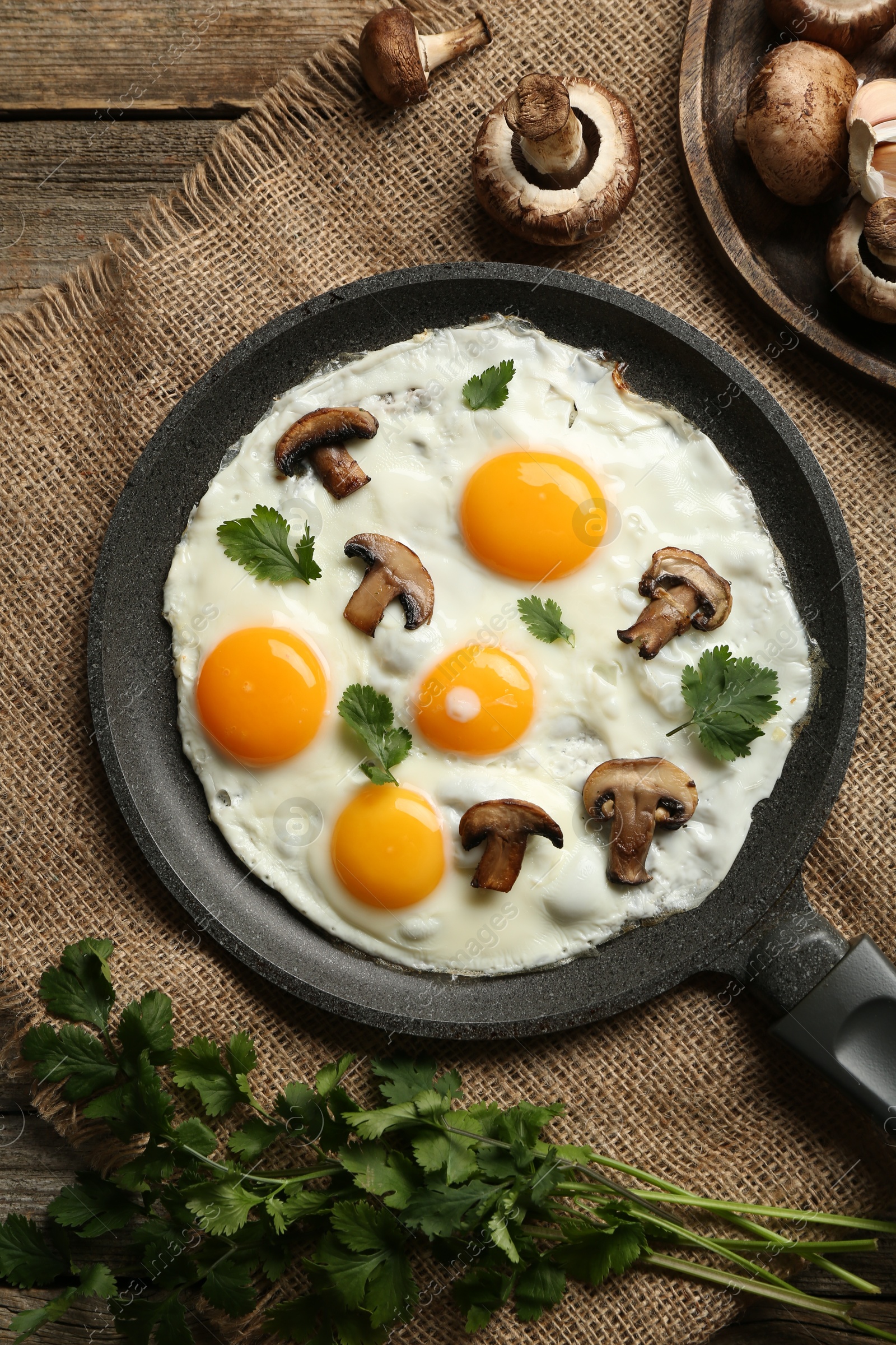 Photo of Tasty fried eggs with mushrooms and parsley served on wooden table, flat lay