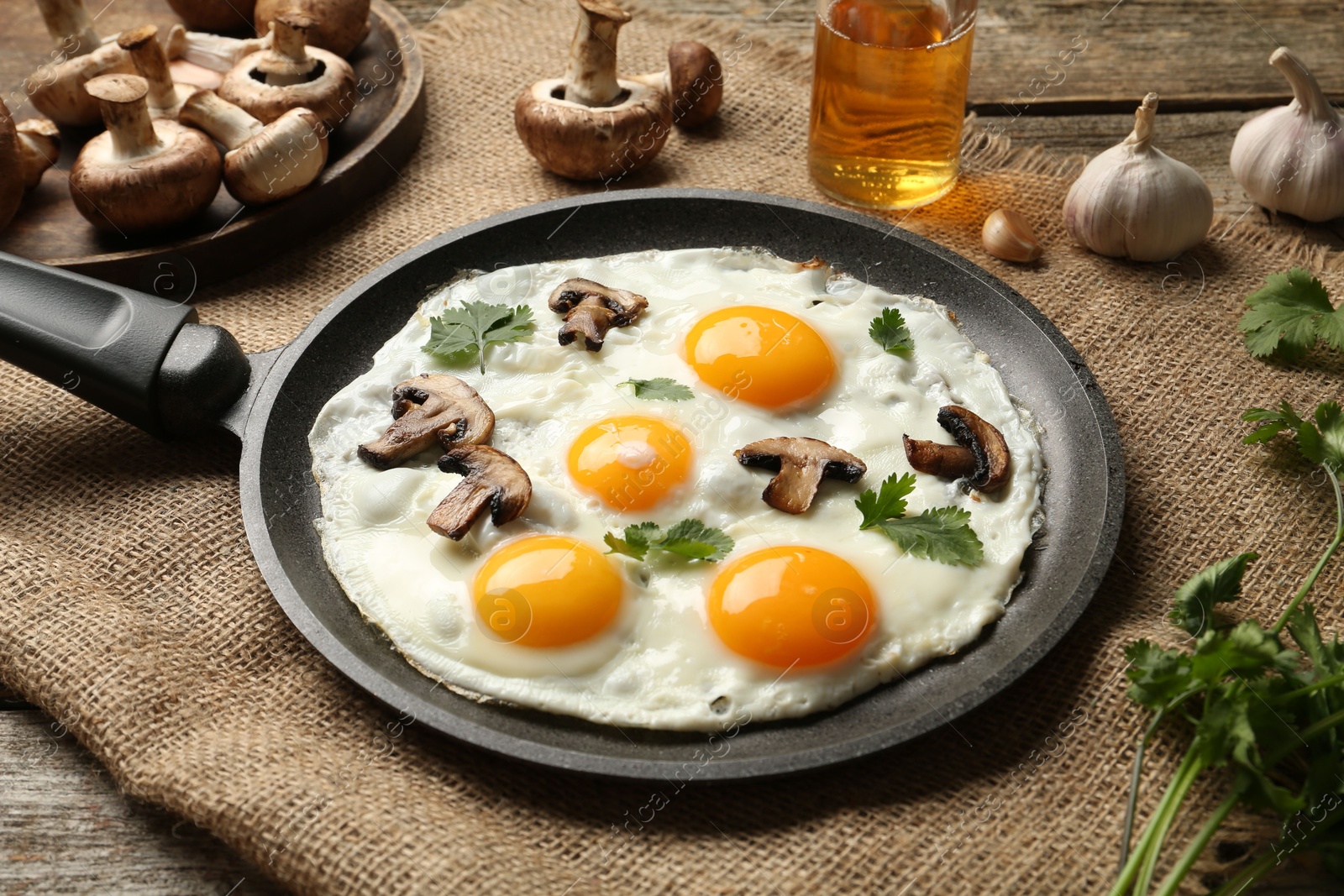 Photo of Tasty fried eggs with mushrooms and parsley served on wooden table