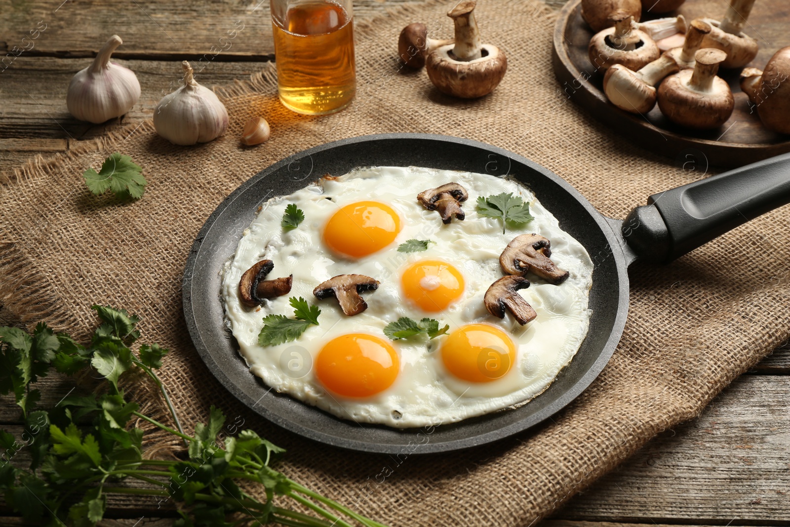 Photo of Tasty fried eggs with mushrooms and parsley served on wooden table