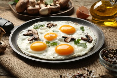 Photo of Tasty fried eggs with mushrooms and parsley served on wooden table, closeup