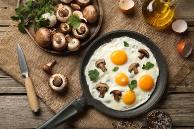 Photo of Tasty fried eggs with mushrooms and parsley served on wooden table, flat lay