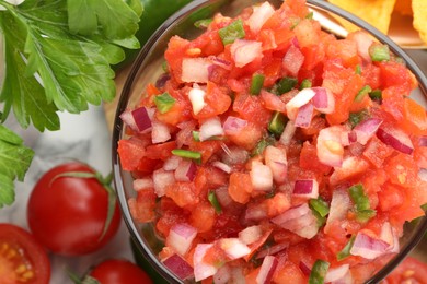 Delicious salsa in bowl and ingredients on table, top view