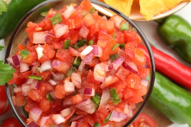 Delicious salsa in bowl and ingredients on table, top view