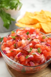 Delicious salsa in glass bowl on table, closeup