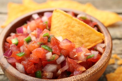 Photo of Delicious salsa and nacho chip in bowl on table, closeup