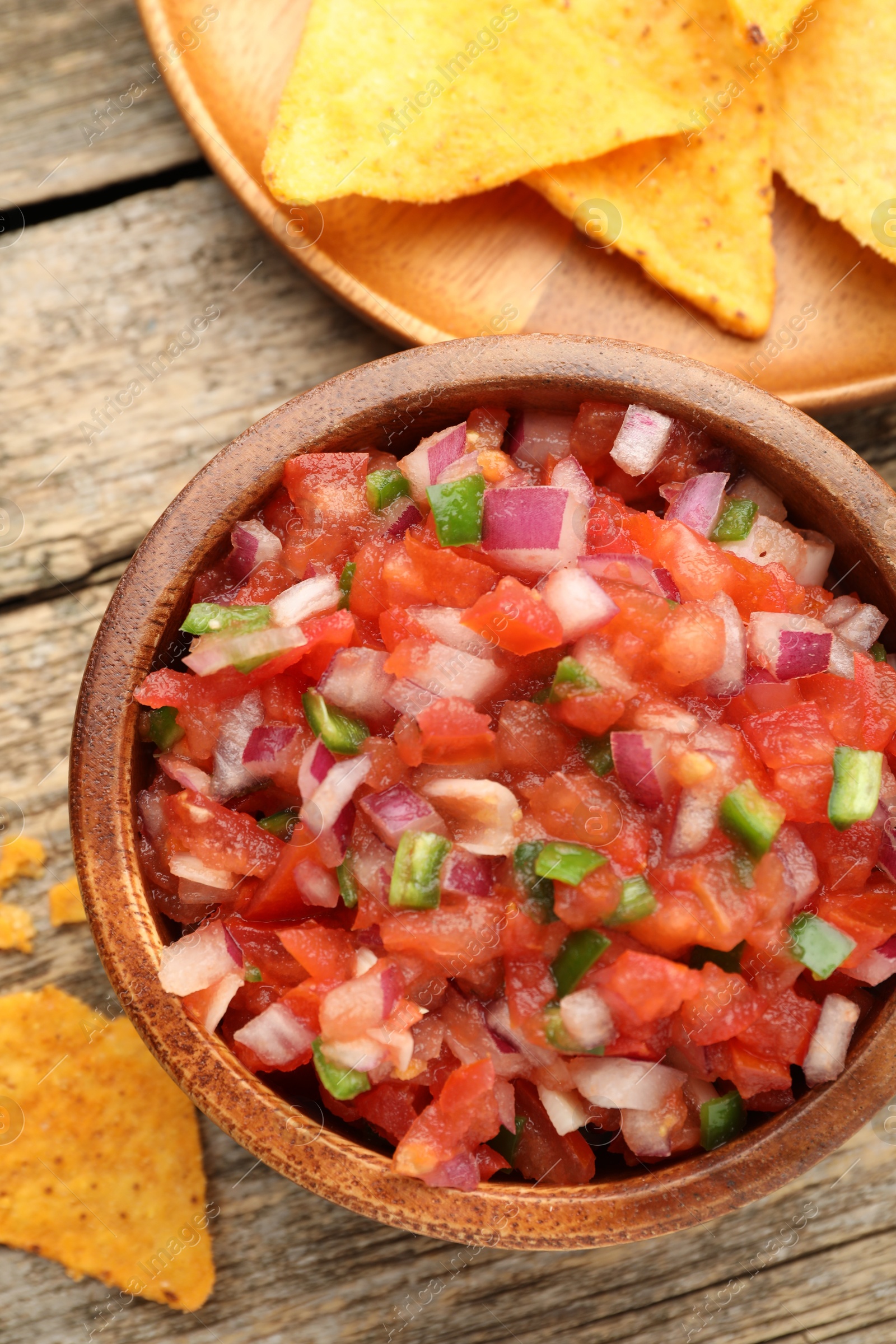 Photo of Delicious salsa in bowl and nacho chips on wooden table, flat lay