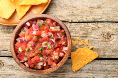 Delicious salsa in bowl and nacho chips on wooden table, flat lay