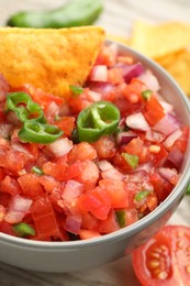 Delicious salsa and nacho in bowl on table, closeup