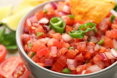 Delicious salsa and nacho in bowl on table, closeup