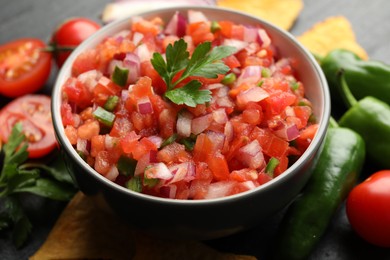 Photo of Delicious salsa in bowl and ingredients on grey table, closeup