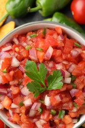 Delicious salsa in bowl and ingredients on table, top view