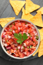 Photo of Delicious salsa in bowl and nacho chips on grey table, flat lay