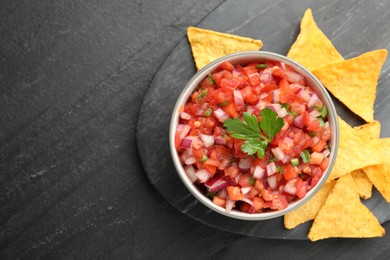 Photo of Delicious salsa in bowl and nacho chips on grey table, flat lay. Space for text