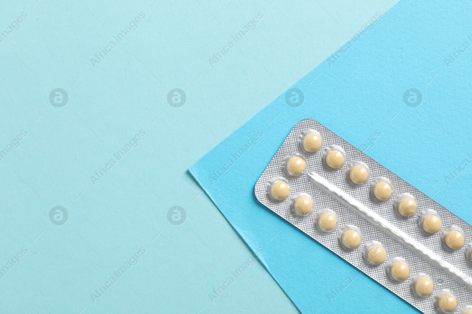 Photo of Blister of contraceptive pills on light blue background, top view. Space for text