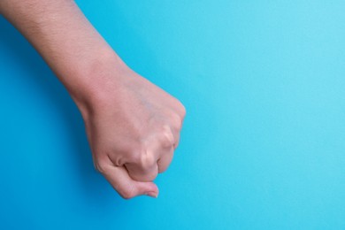 Photo of Woman with visible hand veins on light blue background, closeup. Space for text