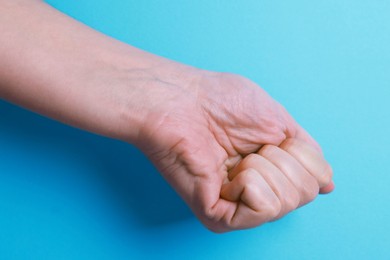 Photo of Woman with visible hand veins on light blue background, closeup