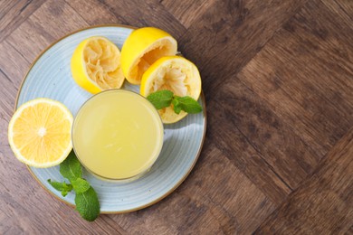 Photo of Glass of lemon juice and fresh fruits on wooden table, top view. Space for text