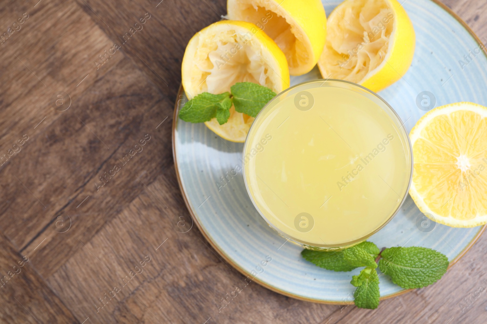 Photo of Glass of lemon juice and fresh fruits on wooden table, top view. Space for text