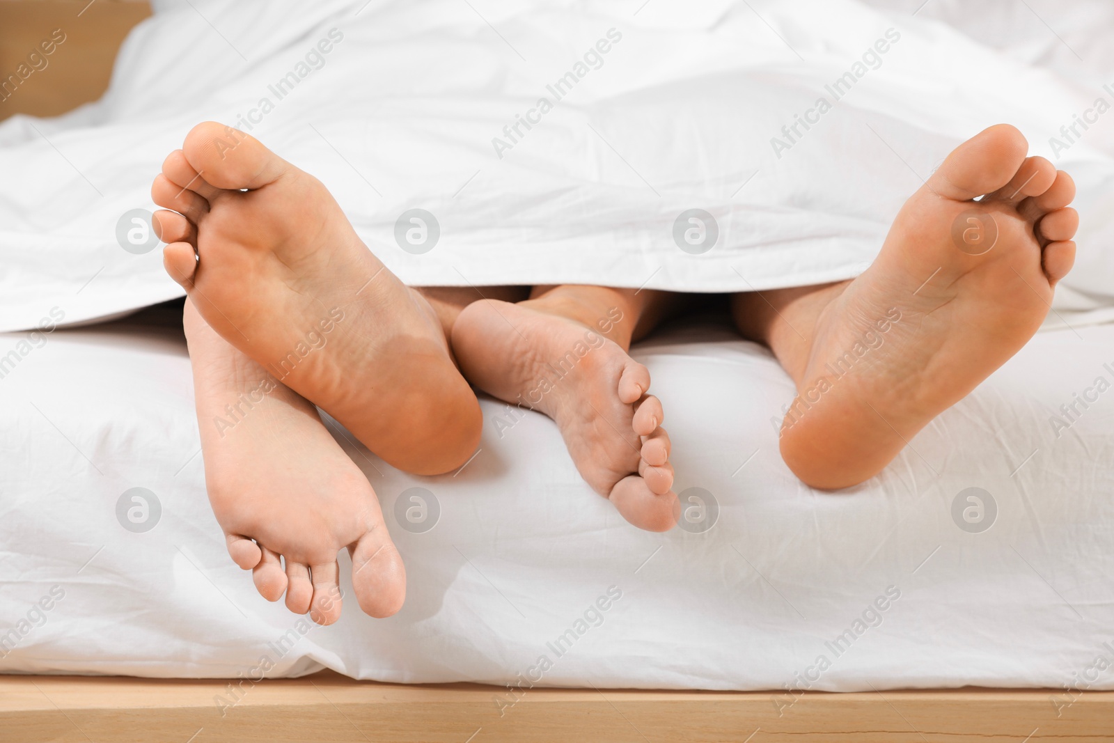 Photo of Couple lying in bed with white sheets, closeup