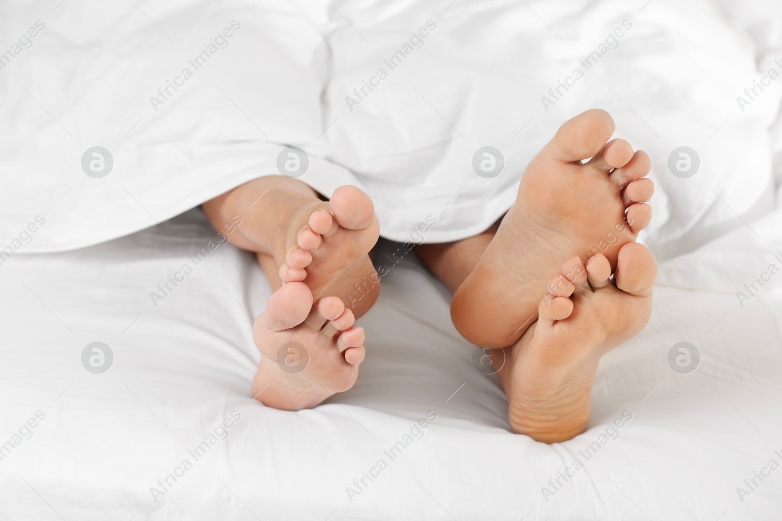 Photo of Couple lying in bed with white sheets, closeup