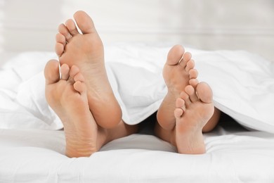 Photo of Couple lying in bed with white sheets, closeup