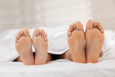 Photo of Couple lying in bed with white sheets, closeup