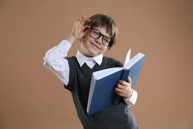 Photo of Learning alphabet. Little boy with book on brown background