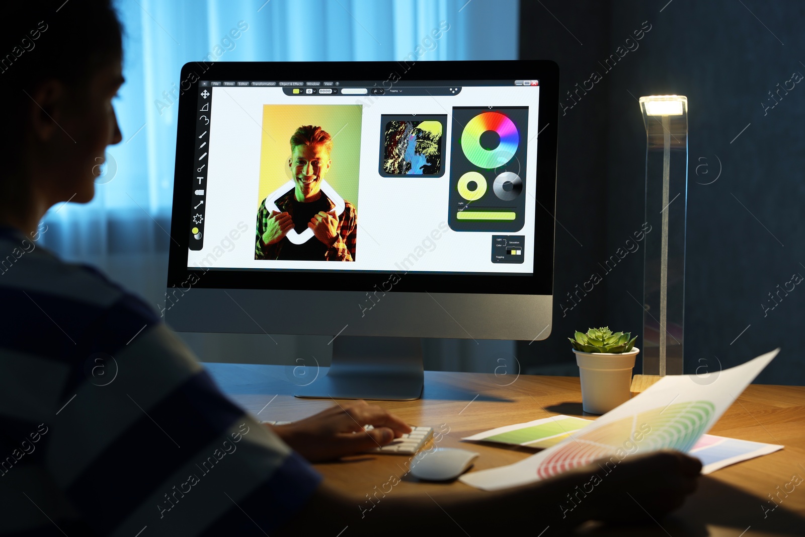 Photo of Designer with color palette working indoors at night, closeup