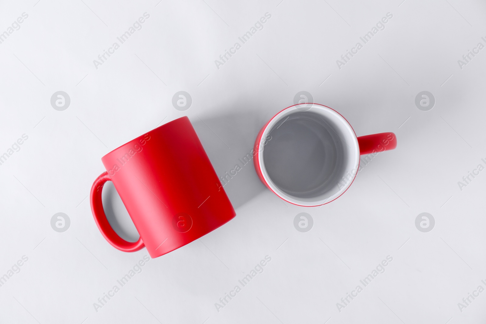 Photo of Two blank red mugs on white background, top view. Mockup for design