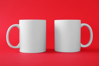 Two blank white mugs on red background. Mockup for design