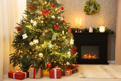 Photo of Beautifully decorated Christmas tree, gifts and fireplace in room