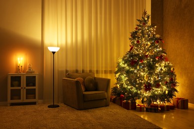 Photo of Cozy room with beautiful Christmas tree, armchair and lamp. Interior design for holiday