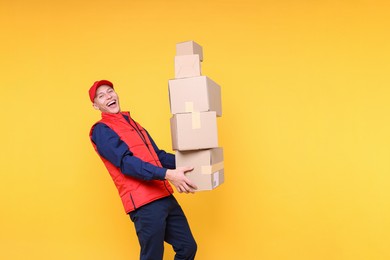 Photo of Happy postman with parcels on yellow background. Space for text