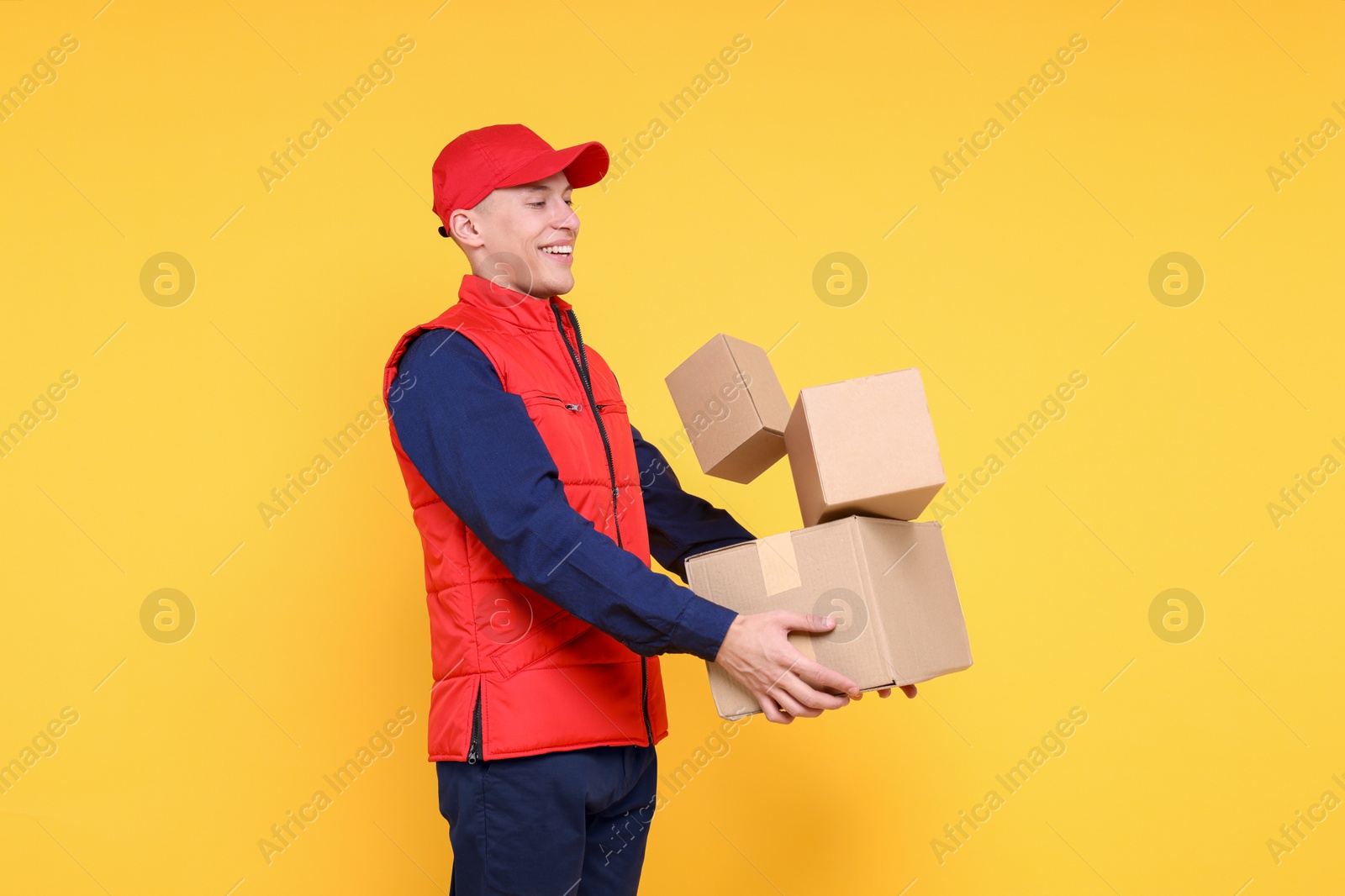 Photo of Happy postman with parcels on yellow background