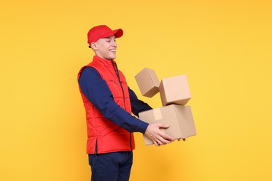 Photo of Happy postman with parcels on yellow background