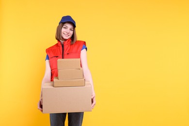 Photo of Happy postwoman with parcels on yellow background. Space for text