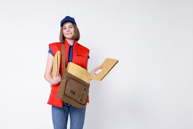 Photo of Happy postwoman with bag and envelopes on white background. Space for text