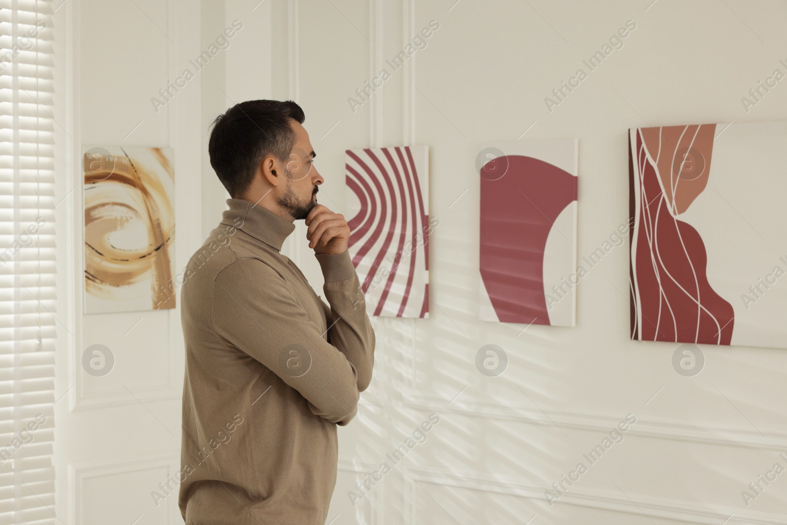 Photo of Man studying beautiful artwork in modern gallery