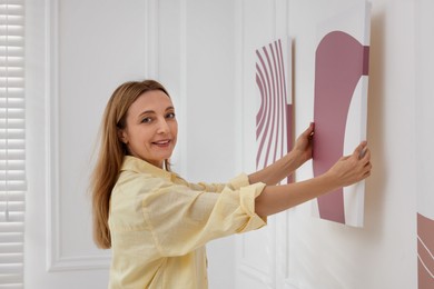 Photo of Woman hanging painting on wall in art gallery