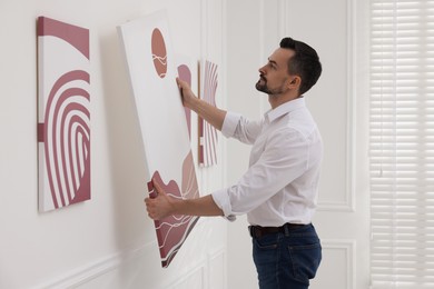 Photo of Man hanging painting on wall in art gallery