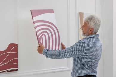 Photo of Man hanging painting on wall in art gallery