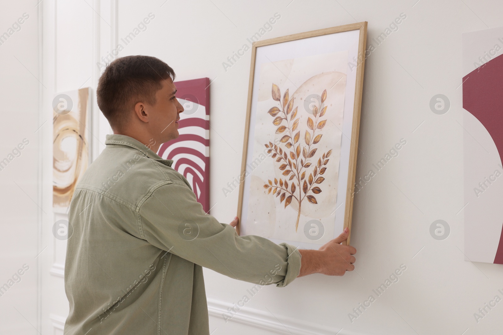 Photo of Man hanging painting on wall in art gallery