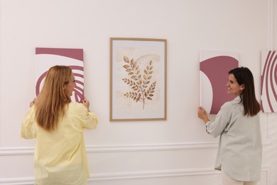 Photo of Women hanging paintings on wall in art gallery