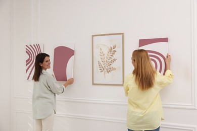 Photo of Women hanging paintings on wall in art gallery