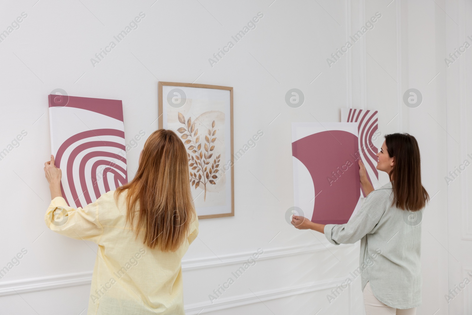 Photo of Women hanging paintings on wall in art gallery