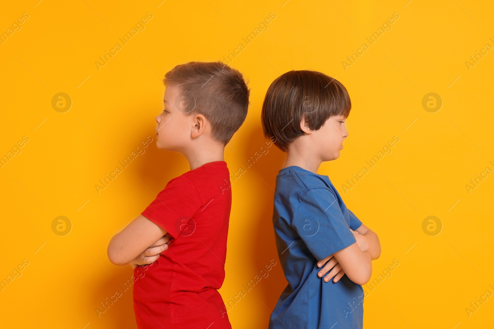 Photo of Upset brothers turned away from each other on orange background