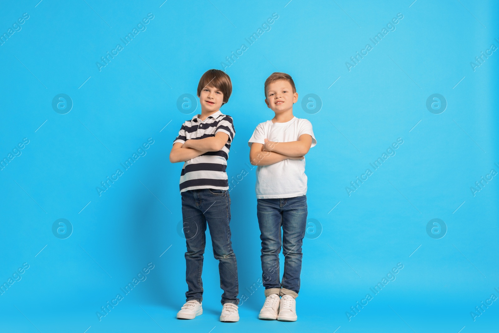 Photo of Cute brothers posing on light blue background