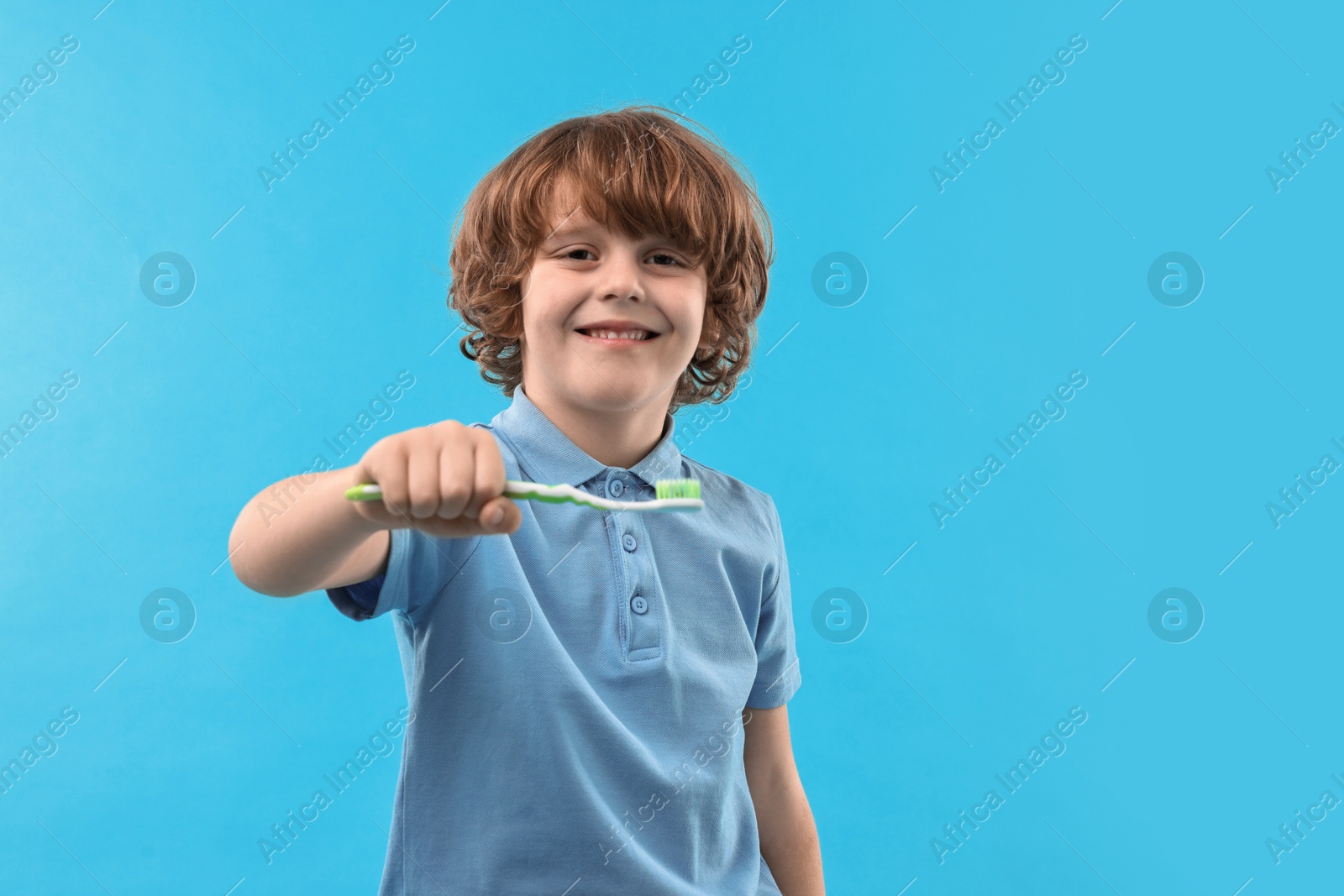 Photo of Cute boy with toothbrush on light blue background, space for text